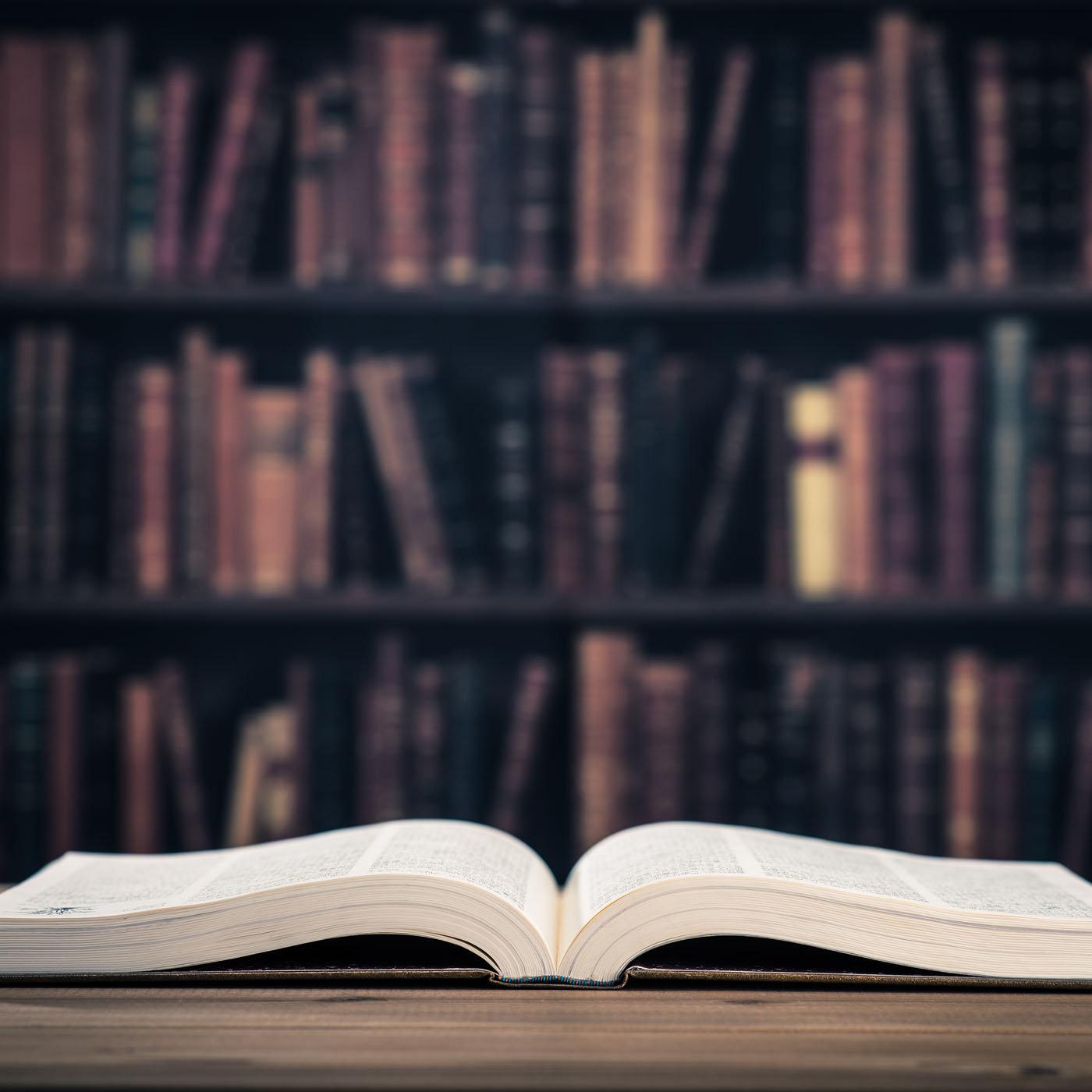 open book on table with bookshelf in background