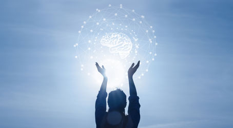 Silhouette of woman with hands up toward brain outline