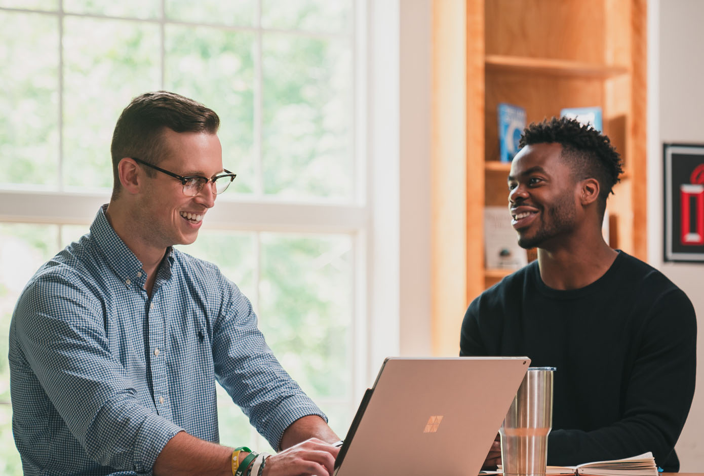 Two students interacting over laptop