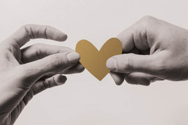 two hands holding gold heart