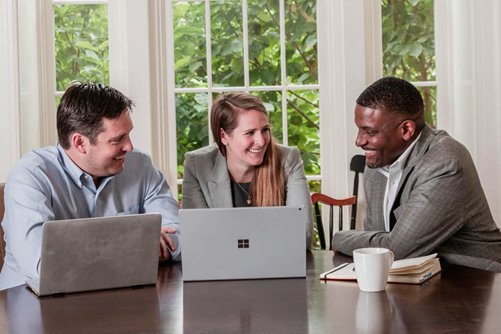 Three students in a conference room with laptop